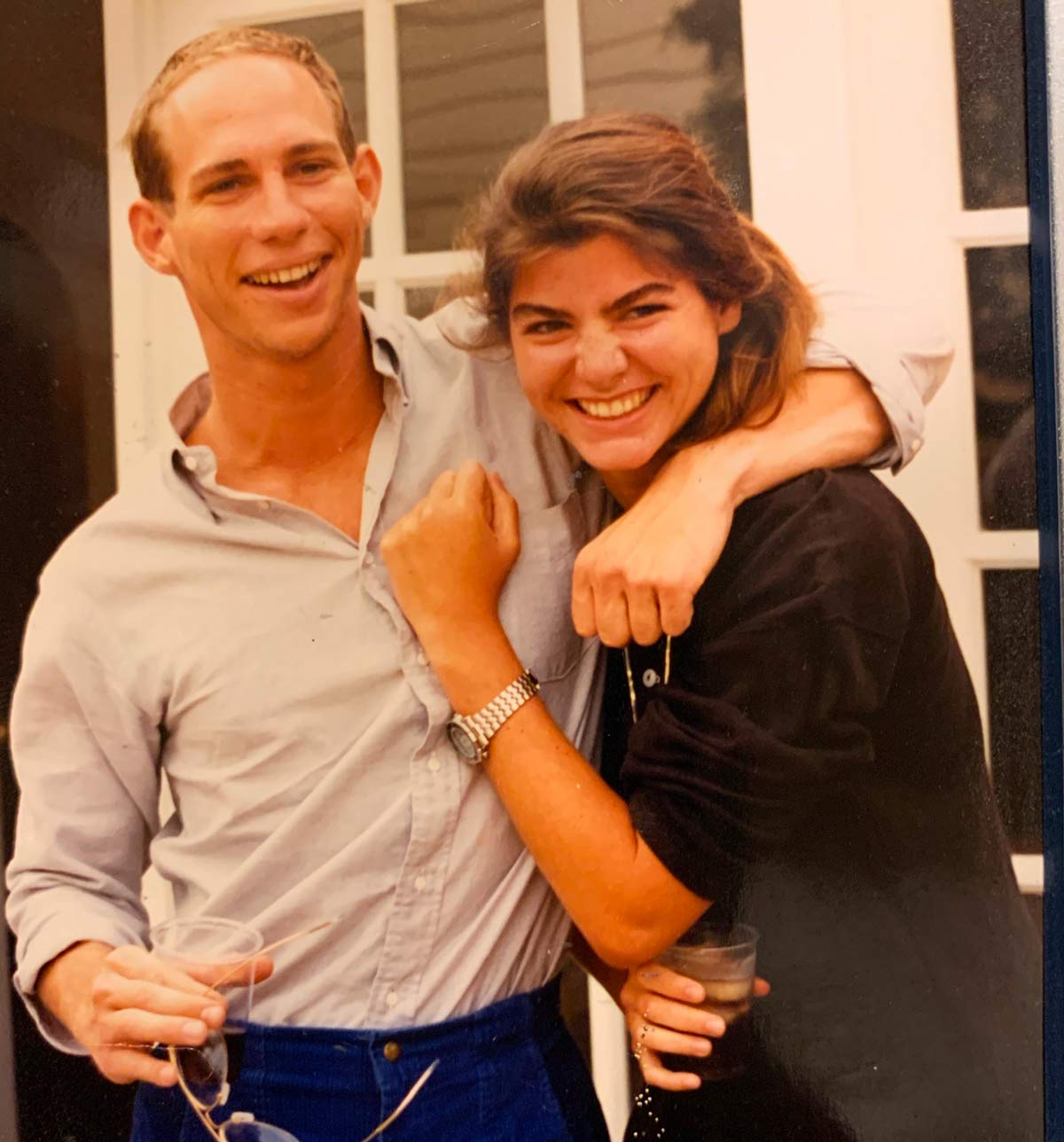 Man with his arm around woman in front of white doors