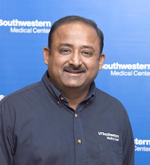 Man in UTSW button down shirt with dark hair and mustache