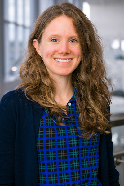 Woman with dark hair, floral pattern dress wearing a lab coat