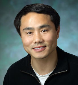 Dr. Pan, a smiling man with dark hair wearing a black jacket over a white tshirt.