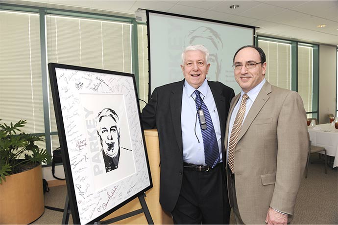 two men standing side-by-side next to drawing of a man