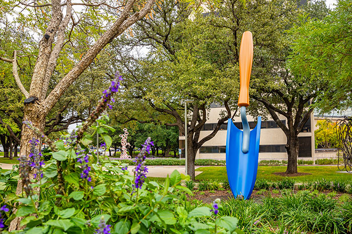 Blue bladed trowel with plants in front of it