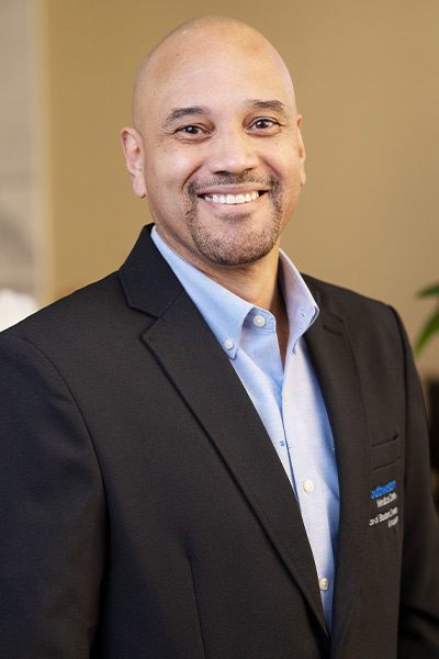 smiling balkd man in gray suit, blue shirt 