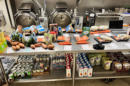 Industrial kitchen island/table laid out with prepared food kits ready to be packaged.