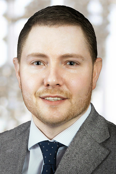 Sean Yates, M.D. headshot - white man with short brown hair and beard wearing gray suit with blue tie