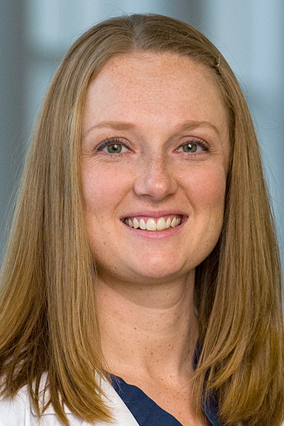 Amanda Virginia headshot - smiling woman with long staight blond hair wearing white coat and blue top