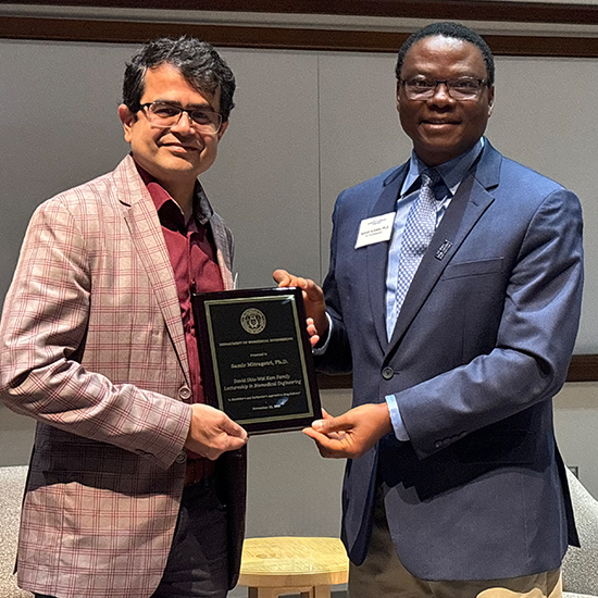 two men smiling, holding award plaque between them