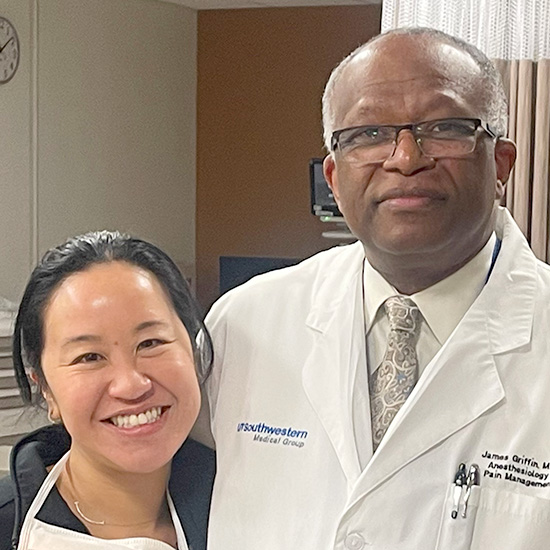 smiling young Asian female doctor stands next to older black doctor in scrubs