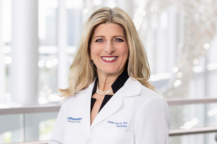 Smiling woman with long blond hair, wearing a white UT Southwestern Medical Center lab coat.