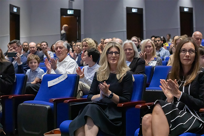 Two women in seated in the audience applaud.