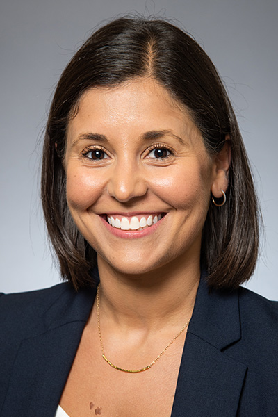Smiling woman with shoulder-length dark hair, wearing a dark jacket.
