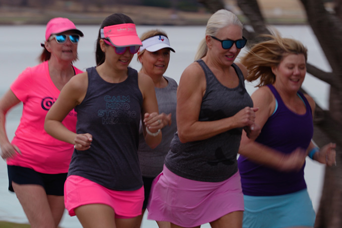 group of 5 women running in a park