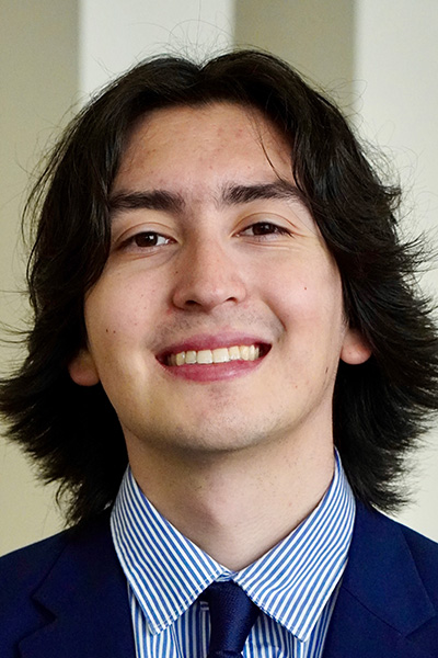 Smiling man with dark hair, wearing a blue jacket.