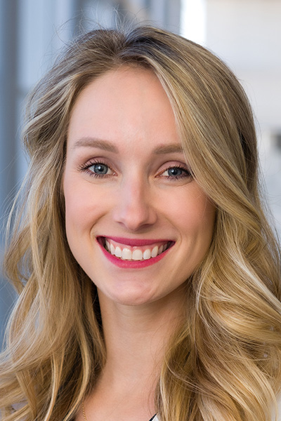 Smiling woman with blonde hair, wearing red lipstick.