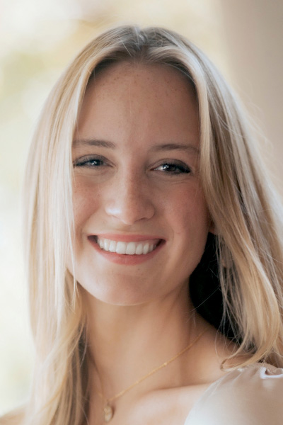 Smiling woman with blonde hair, wearing a white blouse.