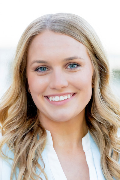 Smiling woman with long blonde hair, wearing a white blouse.