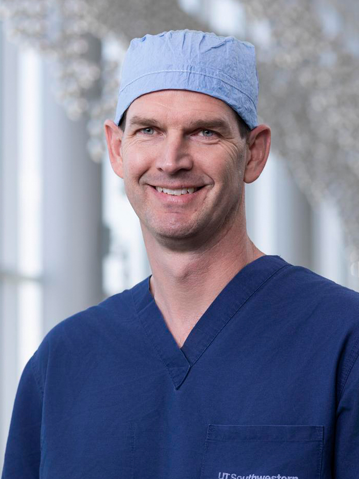 Smiling man wearing blue UT Southwestern scrubs and blue surgical cap.