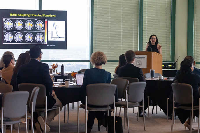 Audience listens to speaker as she discusses scans shown on a screen.