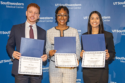 3 scholarship winners show off their award certificates in front of UTSW logo backdrop; from left: Ali Sadek, D'Nai Thomas, and Mayuri Vaish