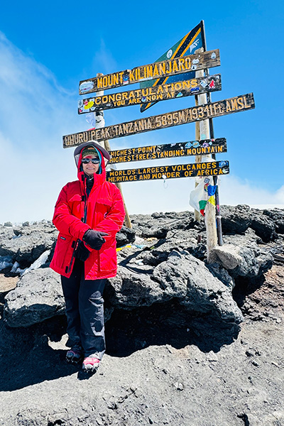 Dr. Vemulapalli poses at peak marker sign on Mt. Kilimanjaro