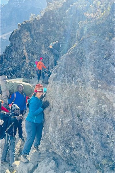 group of mountain climbers cling to a rocky cliff face during ascent