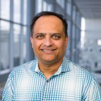 Amol Patwardhan, M.D., Ph.D., southeast Asian man, brown hair, blue and white checkered shirt, smiling