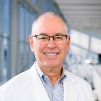 Javier Marull, M.D., white man, bald, wearing glasses, smiling, wearing medical coat