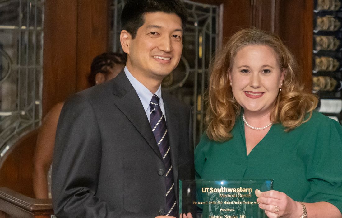 asian man wearing black suit holding award on left