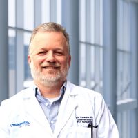 white man with gray hair wearing medical coat