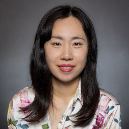 Smiling woman with long dark hair, wearing a print blouse.