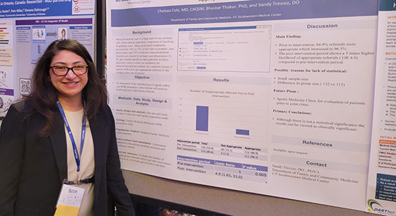 A woman stands in front a research poster at a conference