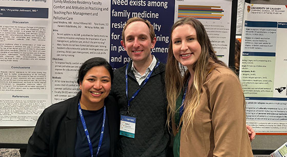Three people pose in front research posters at a conference
