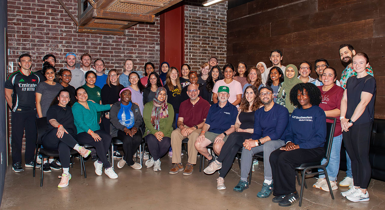 A group photo of the current residents in room with brick walls, taken on a faculty retreat