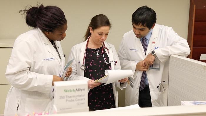 A photo of three doctors in white coats reviewing information on a clipboard
