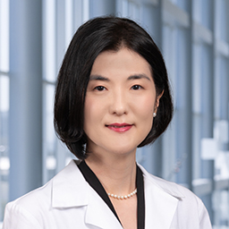 Dr. Laurel Y. Lee wearing a white lab coat standing in the CUH lobby