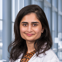 r. Abeera Azam wearing a white lab coat standing in the Clements University Hospital lobby