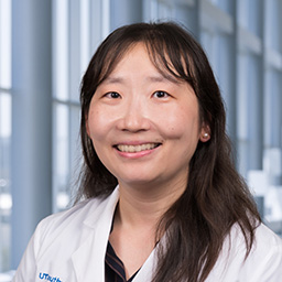 Dr. Yu Cao wearing a white lab coat standing in the Clements University Hospital lobby