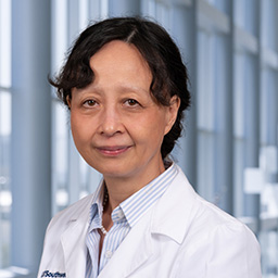 Dr. Jing Chen wearing a white lab coat, standing in the Clements University Hospital lobby