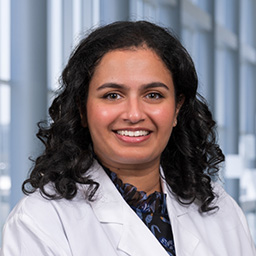 Dr. Anjali Muraleedharan wearing a white lab coate standing in the CUH lobby