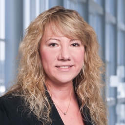 a woman with curly blonde haire wearing a dark jacket