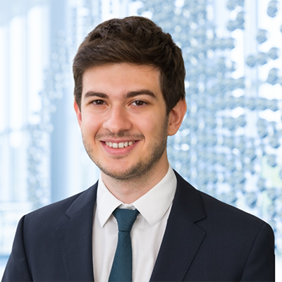 Dr. Karim Seif El Dahan wearing a white shirt with a blue tie and suit jacket standing in the Clements University Hospital Lobby
