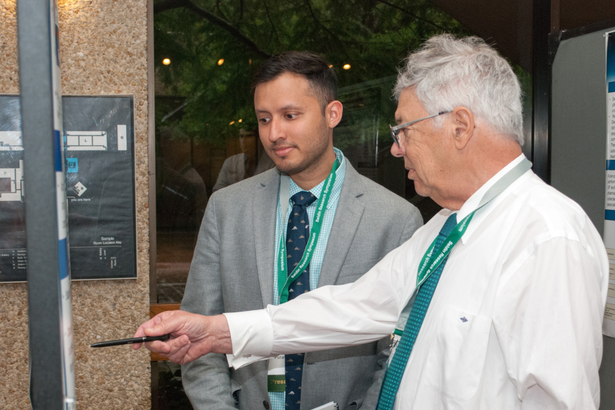 Dr. Michael Brown review poster with a symposium participant