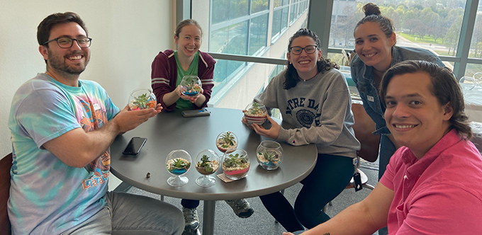 Five people around a table posing with their succelent plants