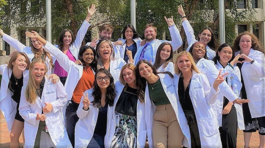 A group of residents in white coats doing a classic Now-Lets-Do-a-Fun-One type of photo