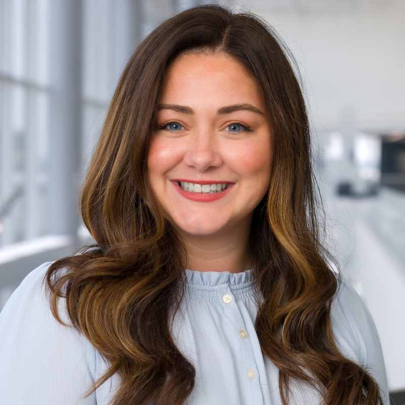 Smiling woman with long brown hair, wearing a blue blouse.