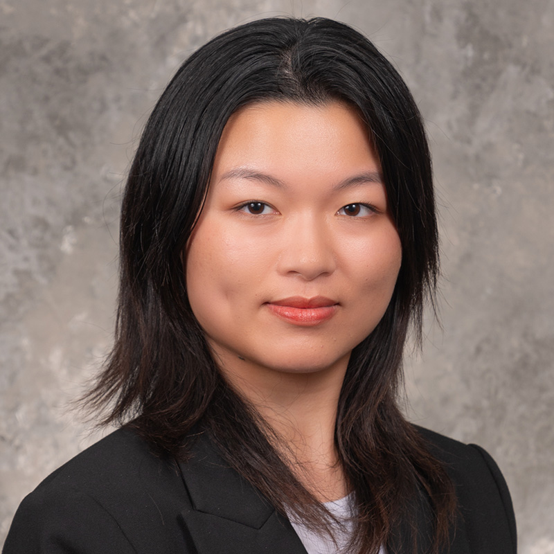 Slightly smiling woman with medium length black hair, wearing a black jacket.