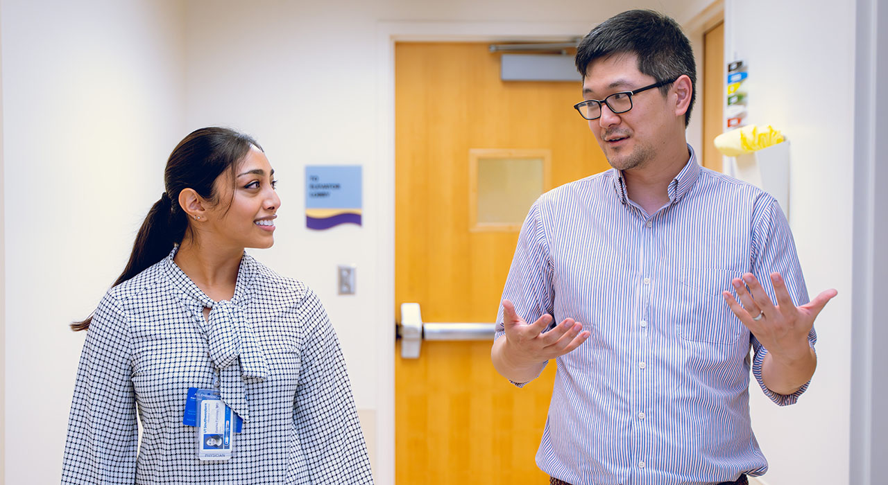 Dr. Su talks with a resident as they walk through a hallway