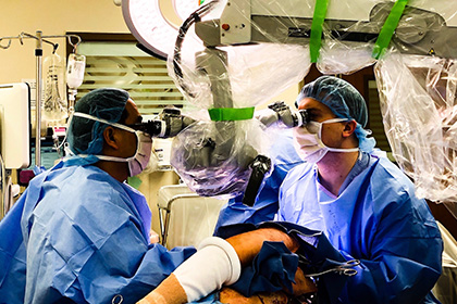 Drs. in scrubs and masks performing microsurgery.