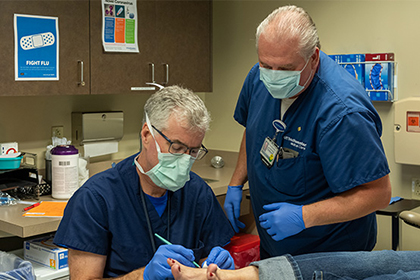 Two doctors wearing scrubs and masks working on a patients foot.