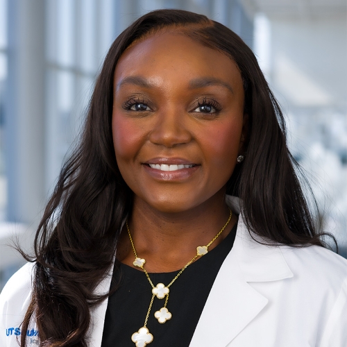 Dr. Rita Shelby headshot, smiling woman with long black hair, white and gold chain necklace and white lab coat